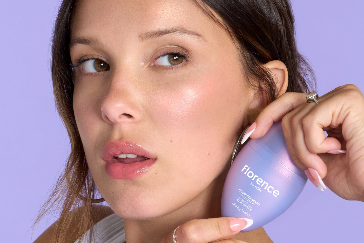 Millie Bobby Brown holding bottle of Glow Forward Glaze Drops